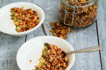 Tasty granola with yogurt in a plate and herbal tea in a glass mug for healthy breakfast. Apartment latitude, top view. Diet, weight loss, healthy eating concept