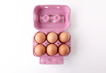 Top view of six brown eggs on box