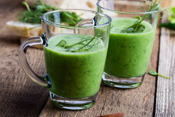 Green pea cream soup in glass mug with sprouts on top