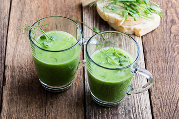 Green pea cream soup in glass mug with sprouts on top
