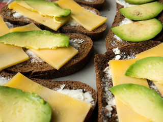 Sandwiches of avocado and cheese on black bread