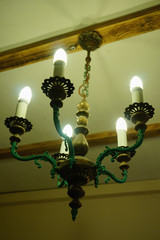 Old chandelier with five lamps hangs on the ceiling with a pre-revolutionary house. 