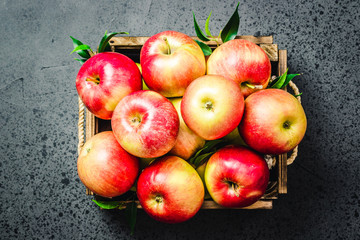 Raw apples in wooden box on concrete background. Top view, space for text.