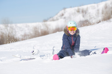 Fototapeta na wymiar Picture of athlete woman in helmet sitting at snowdrift