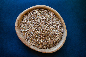Buckwheat Grains in Wooden Jar Placed on Deep Blue Background Surface