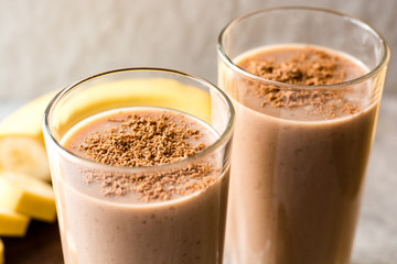 Chocolate banana smoothie in glass on gray stone background