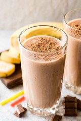 Chocolate banana smoothie in glass on gray stone background