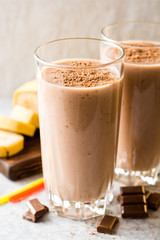Chocolate banana smoothie in glass on gray stone background