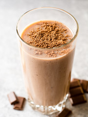 Chocolate banana smoothie in glass on gray stone background