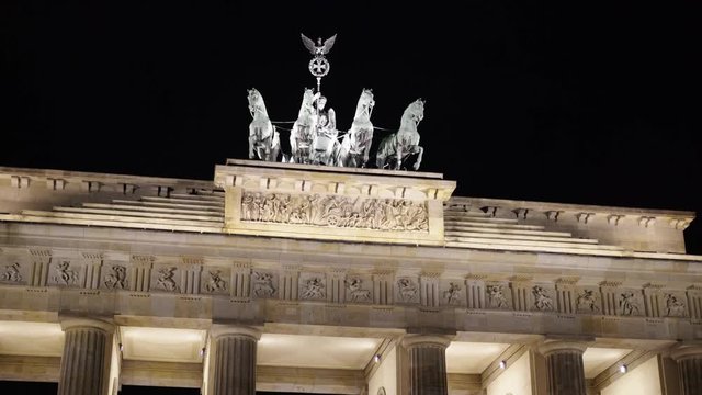 Real time tilt up medium shot of the Brandenburg Gate in Potsdam, Germany. It is a famous tourist place with busy people traffic. Night time