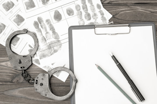 handcuffs with fingerprints on a wooden background. arrest. detention of a criminal.
