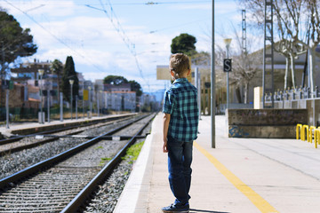 boy waiting for train at railway station in spring