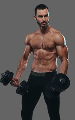 Fototapeta na wymiar A Muscular guy working out with dumbbells. Isolated on a gray ba