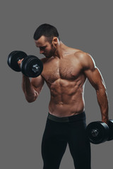 Naklejka na ściany i meble A Muscular guy working out with dumbbells. Isolated on a gray ba