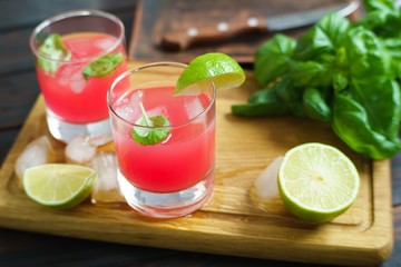 Refreshing cold strawberry cocktail with lime slices and basil served with ice cubes. Summer beverages