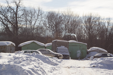 Winter landscape with garages and snow-covered cars. Frosty day at the edge of the city.