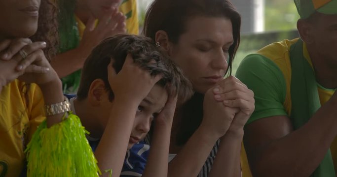 Sports enthusiasts anxiously watching televised match at home, slow motion