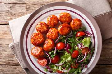 Delicious food: fried chicken meatballs salad of tomato, lettuce and onion close-up on a plate. horizontal top view