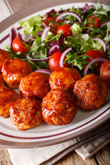 Glazed chicken meatballs with fresh vegetable salad close-up. vertical