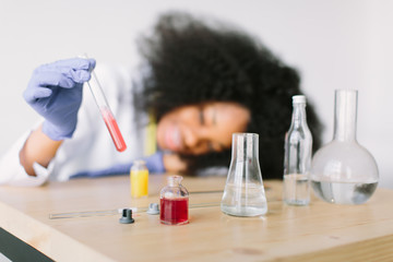 Young beautiful African American girl doctor in a white coat with a stethoscope. sitting at a table...