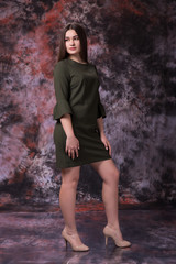 Fototapeta premium Beautiful plump girl in a green dress posing over marble colored background. Fashion photo. Plus size Model