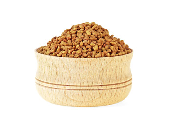 Fenugreek seeds in wooden bowl on white background