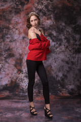 Thin Woman with red jacket standing on over marble colored background. Fashion photo.
