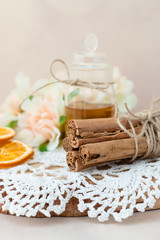 Made at home from orange oil with cinnamon perfume in a glass jar. Slices of dried orange, dried cinnamon and flowers. Crocheted white napkin. Perfumer.Natural and healthy cosmetic. Wooden background.
