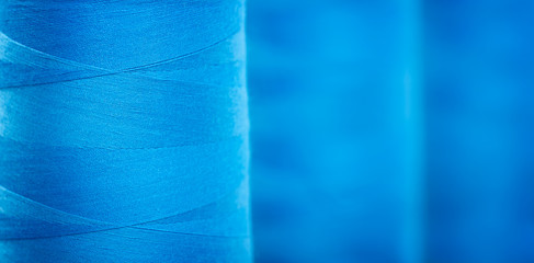 Blue textured web banner background, Close-up bobbins with blue colored thread for industrial...