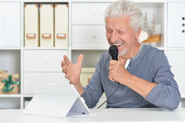 senior man singing karaoke with tablet