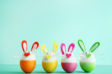 Eggs with funny rabbit faces on mint background