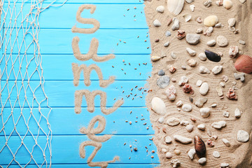 Word Summer with beach sand and seashells on blue wooden table