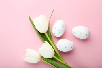 White tulips with easter eggs on pink background