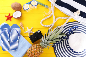 Beach accessories with pineapple on yellow wooden table