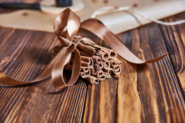 cinnamon sticks tied with brown ribbon on wooden background