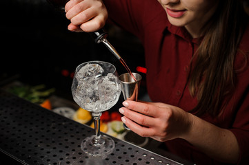 Woman barman pouring bitter for making an Aperol syringe cocktail