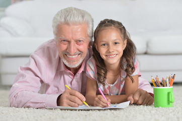 Happy grandfather with granddaughter drawing together