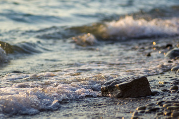 pebble stones on the sea beach, the rolling waves of the sea with foam