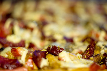 homemade pizza with peppers, plums, ham, sausage, cheese and spices, closeup