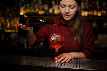 Female barman pouring a dry wine making an Aperol syringe cocktail