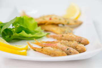 Fried fish on dish with lemon and salad. Typical sicilian food