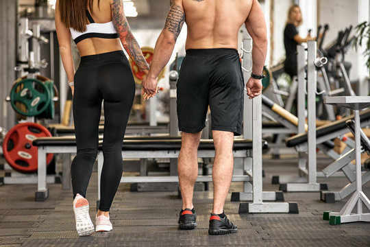 Back view of two young lovers in modern gym