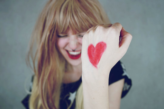 Chica joven con un corazón rojo pintado en su mano 