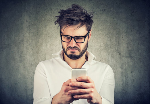 Exasperated man watching phone looking disgusted