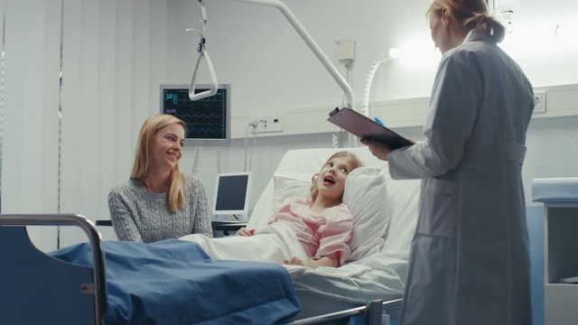 Recovering Little Girl Lies on a Bed In the Hospital, Friendly Doctor With Clipboard Asks Where it Hurts, Mother Sits Beside Bed. Shot on RED EPIC-W 8K Helium Cinema Camera.