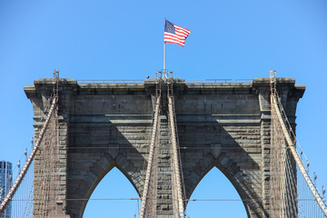 Fototapeta premium low angle view of flags on top of a bridge tower against clear blue sky