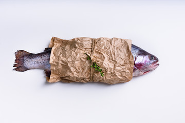 Raw salmon wrapped in paper on white background. Top view.