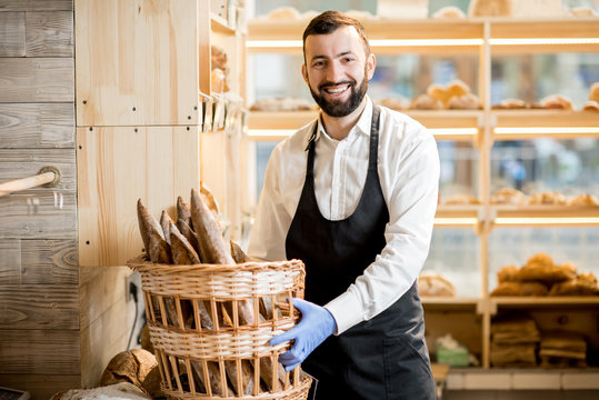 Bread seller with basket full of baguettes in the store with bakery products