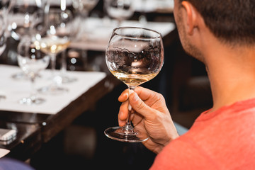 man holds glass of red wine. people consider the color of the wine and try how it smells in different glasses