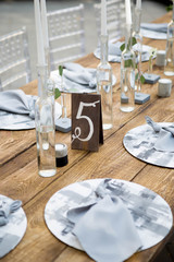 Table with food and flowers on the wedding. Number 5 written on white card stands before the bouquet in the center of dinner table